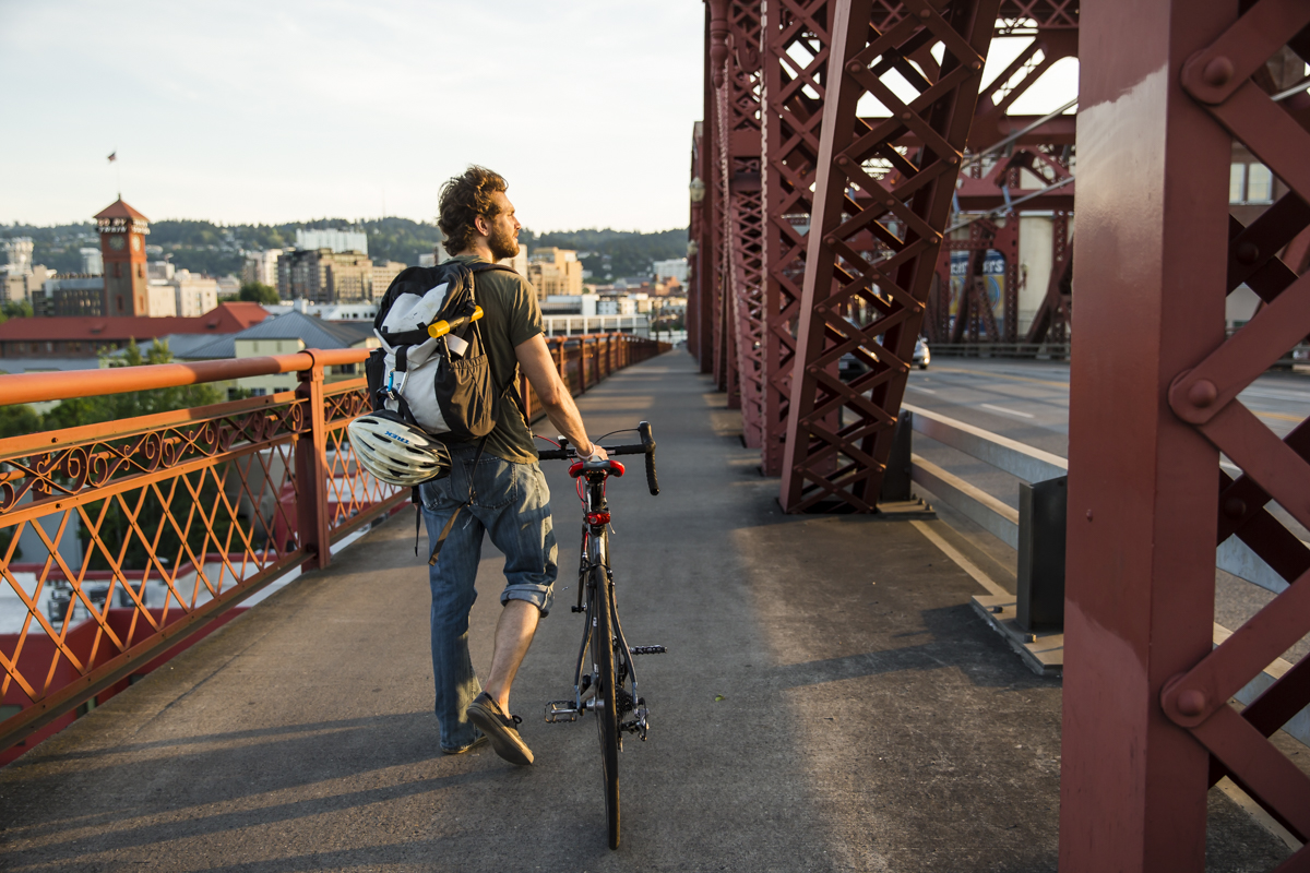 Person with bike walking across bridge