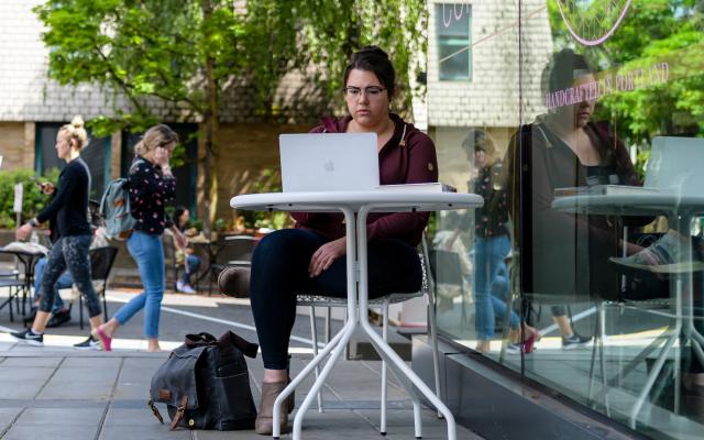 Woman working on a computer outside coco donuts on campus